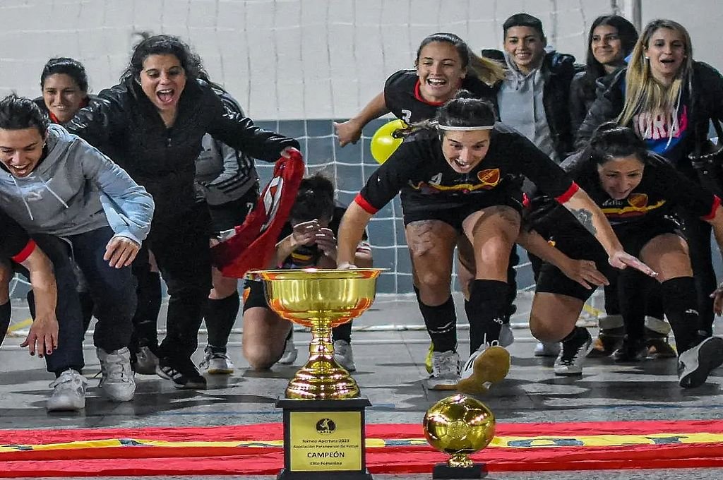 Las jugadoras de Español se zambullen frente al trofeo.  Foto:PRENSA APFS